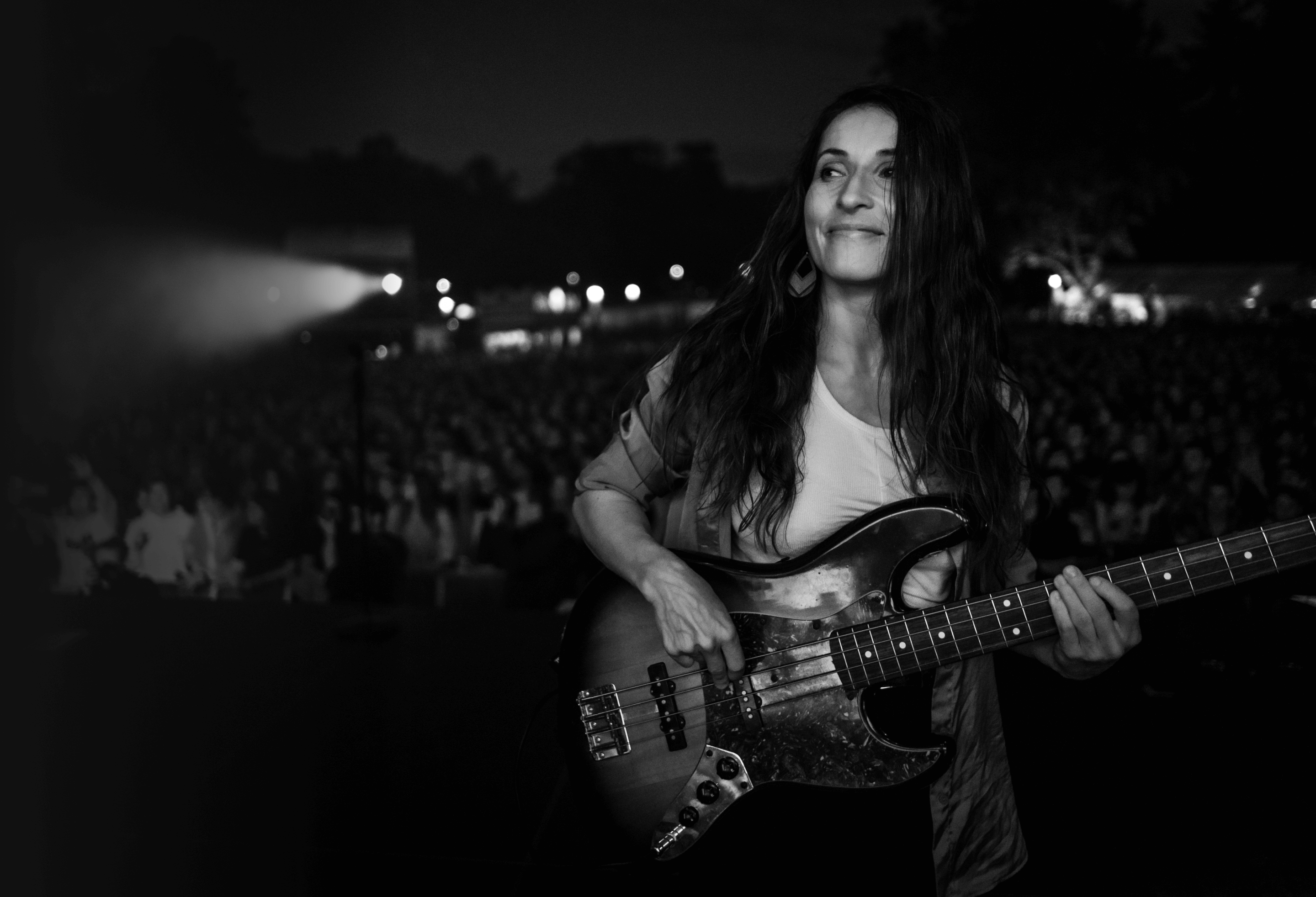 Marlene Lacherstorfer spielt E-Bass auf einer Open-Air-Bühne vor Publikum